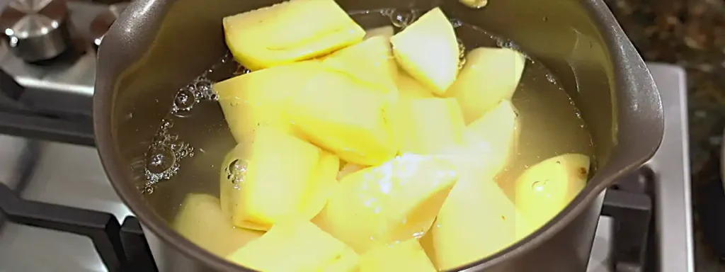 Papas peladas y cortadas cociéndose en agua con sal