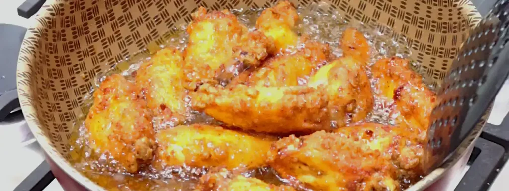 Alitas de pollo rebozadas friéndose hasta dorarse