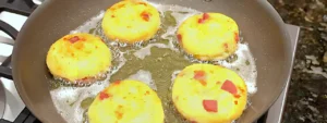 Tortitas de papa con salchicha dorándose en aceite