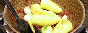 Chiles caribe y cebollas cambray dorándose con tocino
