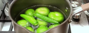 Tomatillos y chiles serranos cociéndose en agua